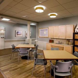 A modern kitchen and dining area with wooden flooring, tables, chairs, and cabinetry.