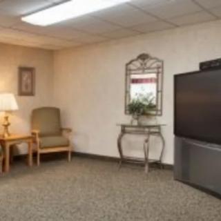 A cozy living room with a television, chair, lamp, and decorative elements.