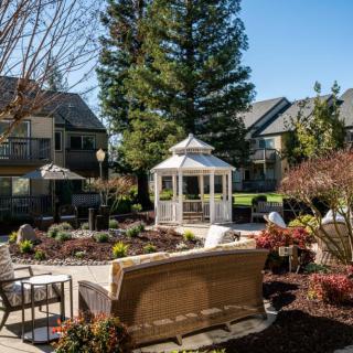 A cozy garden setting with a gazebo and patio furniture surrounded by lush greenery.