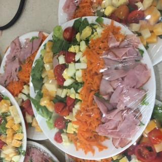 A colorful assortment of salads with ham, cheese, carrots, and fresh vegetables.