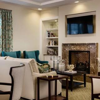A cozy and elegantly designed living room with a fireplace, television, and comfortable seating.