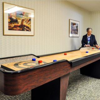 A person playing shuffleboard in an indoor setting.