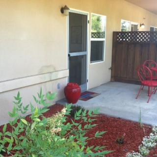 A cozy patio with red outdoor furniture and plants.