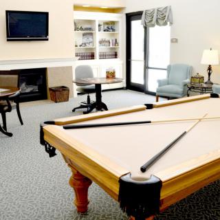 A cozy living room with a billiard table, surrounded by chairs and a television, providing a leisure space for relaxation.