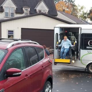 A transport vehicle assisting individuals, parked in front of a house.