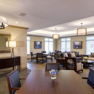 A modern and spacious living area featuring a dining table, comfortable seating, and elegant lighting.