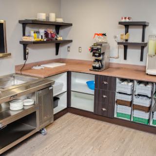 A well-organized and modern commercial kitchen with wooden countertops, shelves for storage, and essential appliances.