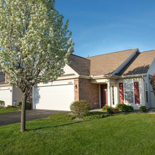 A suburban house with a well-maintained lawn and a blooming tree in the front yard.