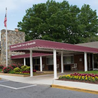 The welcoming entrance of a residential facility, adorned with landscaping and an American flag.