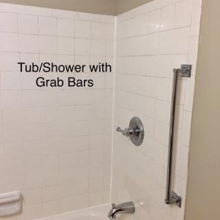 Accessible bathroom with tub/shower and grab bars for safety.