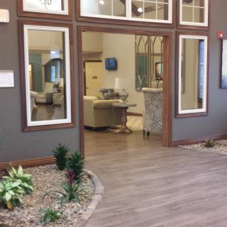 A modern lobby with wood flooring, featuring comfortable seating and indoor plants for a welcoming atmosphere.