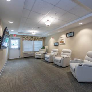 A cozy waiting room with comfortable recliners and a wall-mounted television.
