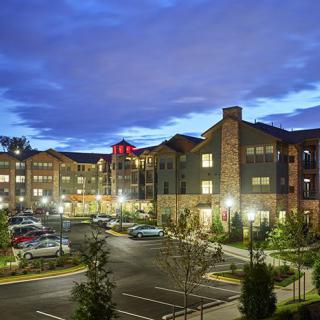 A well-lit hotel building at dusk with a parking lot in the foreground.