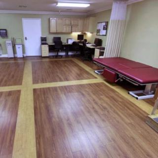 An office space with wooden flooring and workstations in the background.