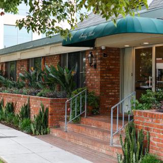 A brick restaurant exterior with green plants and an awning over the entrance.
