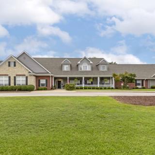 A large suburban house with a well-maintained lawn under a partly cloudy sky.