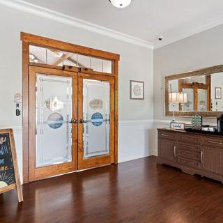 A welcoming entrance with wooden double doors and a mirror, complemented by elegant decor.