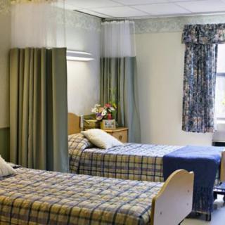 A shared hospital room with two beds and curtains for privacy.