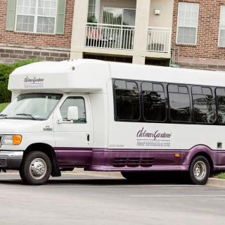 A shuttle bus parked in front of an apartment complex.
