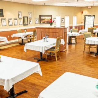 An empty restaurant dining area with neatly arranged tables and chairs on a wooden floor.