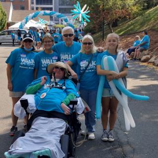 Participants gather for a fundraising walk, showcasing unity and support in teal shirts.