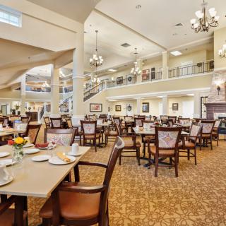 A spacious dining area with elegant decor, featuring tables and chairs arranged under chandeliers.