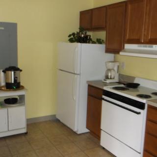 A small kitchen with a refrigerator, stove, and coffee maker.