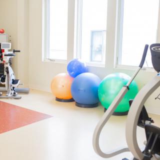 A well-lit gym space with exercise equipment and yoga balls.