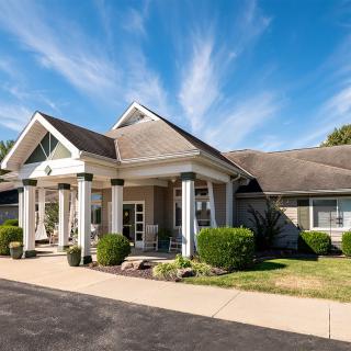 A suburban house with a well-maintained front yard and driveway under a clear blue sky.