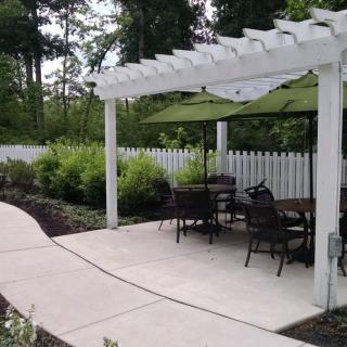 A serene outdoor patio area with a pergola, seating, and garden landscaping.
