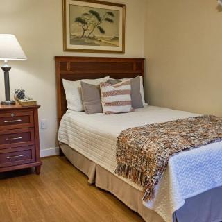 A cozy bedroom with a neatly made bed, nightstand, and lamp.