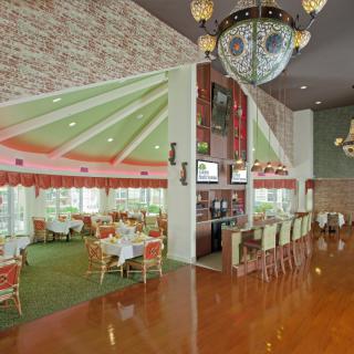 A spacious restaurant interior featuring a bar area and elegant chandeliers.