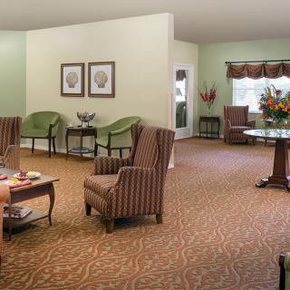 A cozy living room with comfortable chairs, a coffee table, and floral decorations.