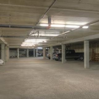 A spacious, well-lit indoor parking garage with several vehicles parked.
