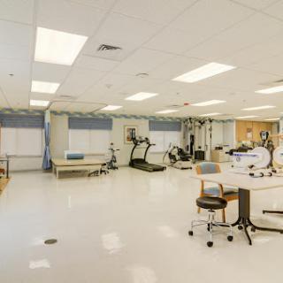 A spacious physical therapy room equipped with various exercise machines and a bright, well-lit environment.