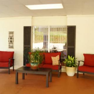 A cozy patio setup with red cushioned seating, a coffee table, and potted plants.