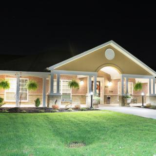 A well-lit house at night with a neatly maintained lawn.