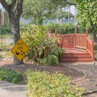 A serene garden pathway featuring a small wooden bridge and a caution sign.