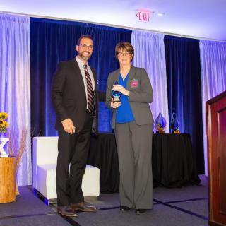 Two people in formal attire standing on a stage during an awards ceremony.
