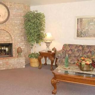 A cozy living room featuring a floral sofa, wooden coffee table with decorative items, and a brick fireplace.