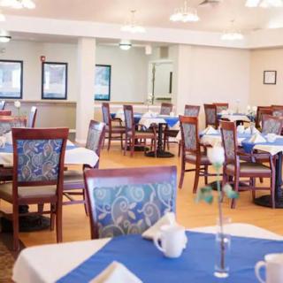 A spacious dining area with neatly arranged tables and chairs, adorned with blue tablecloths.