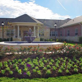 A well-maintained garden with a fountain in front of a large building.