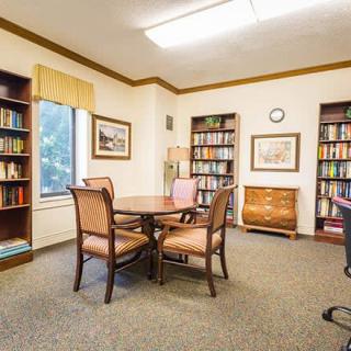 Cozy library reading room with bookshelves and a table with chairs.
