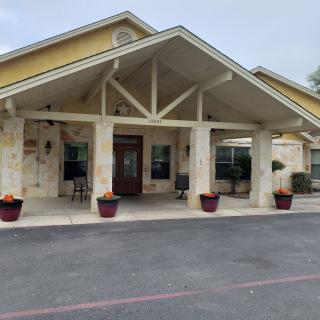 A building entrance with a covered porch and stone facade, featuring potted plants.