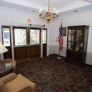 An elegant lobby entrance featuring a chandelier, an American flag, a display cabinet, and comfortable seating.