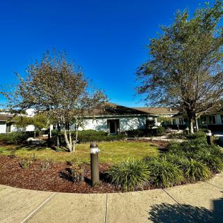 A landscape view of a building surrounded by trees and a garden under a clear blue sky.