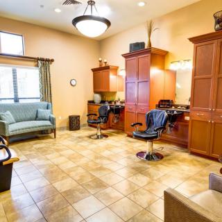 A well-lit salon interior featuring barber chairs, wooden cabinets, and comfortable seating.