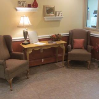 A cozy waiting area with two armchairs, a small table, and decorative elements.