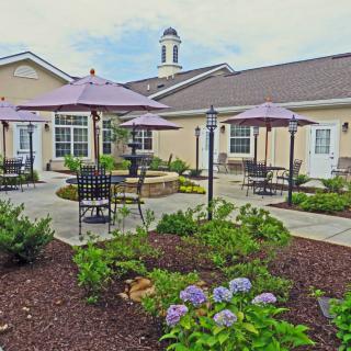 A well-maintained garden patio area with outdoor seating and umbrellas, surrounded by vibrant flowers.