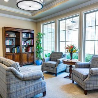 A cozy living room with armchairs and a bookcase by large windows.